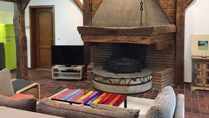 Un interior rústico con chimenea de ladrillo, vigas de madera y una alfombra colorida.