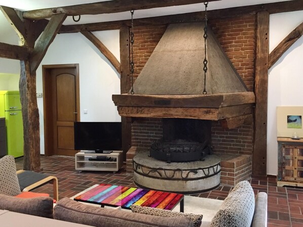 Un interior rústico con chimenea de ladrillo, vigas de madera y una alfombra colorida.