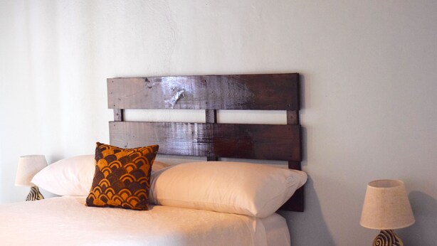 A bed with a wooden headboard, two pillows, and a nightstand with a lamp. - 256 Jamaica (Montego Bay)