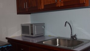 A kitchen with wooden cabinets, a stainless steel sink, and a microwave. - 256 Jamaica (Montego Bay)