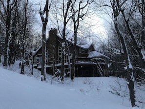 Une grande maison en bois à plusieurs étages, entourée d’arbres couverts de neige.