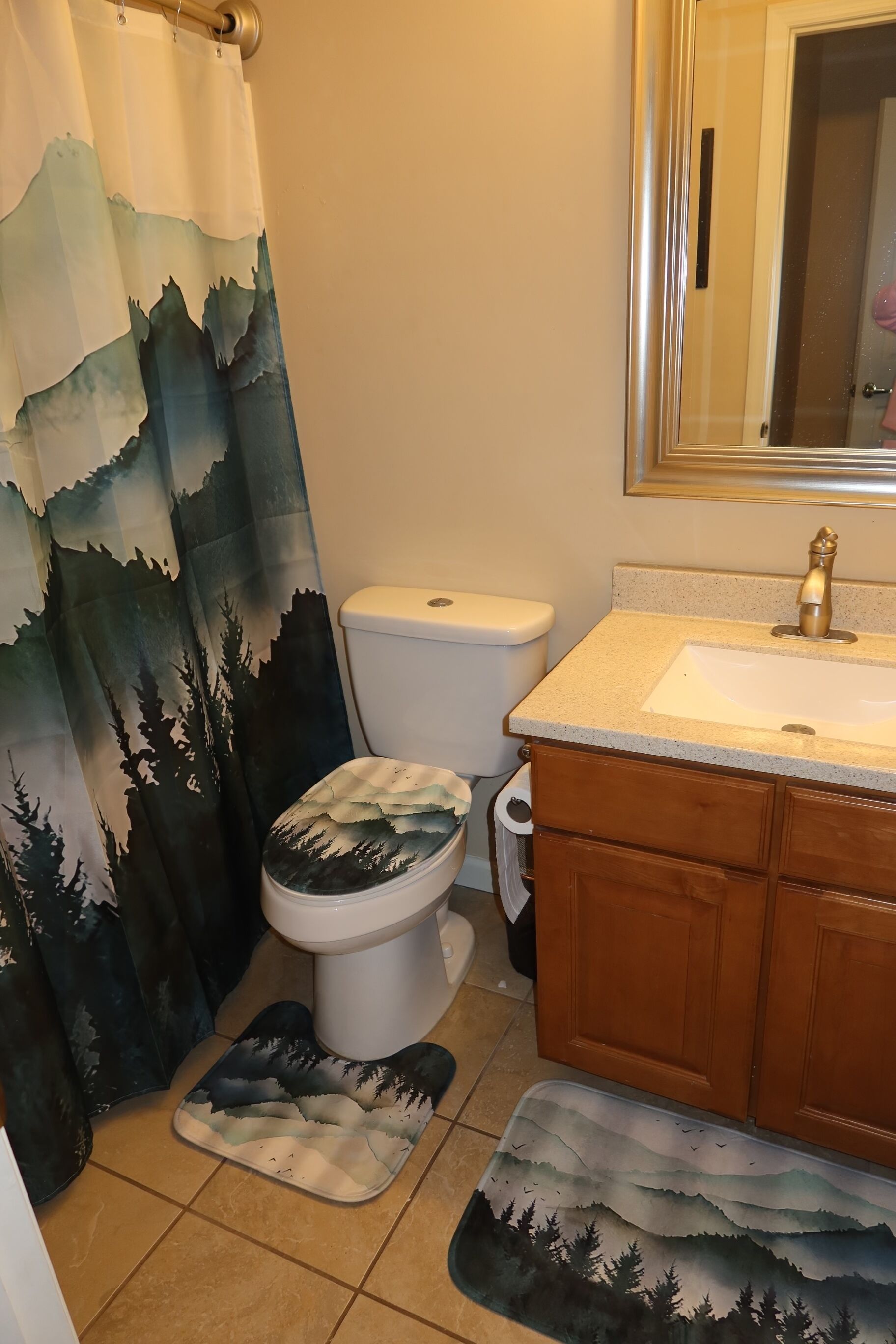 A bathroom with a toilet, sink, and wooden cabinets.