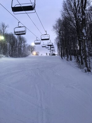 A snow-covered road with a ski lift in the background.