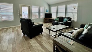 A spacious living room with a large window, a flat-screen TV, and a fireplace. - BEACH FRONT with panoramic views of the Gulf Coast. (Bolivar Peninsula)
