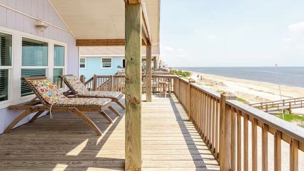A wooden deck with two lounge chairs facing a beach. - BEACH FRONT with panoramic views of the Gulf Coast. (Bolivar Peninsula)