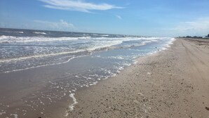 A beach with waves, a clear sky, and a sandy shore. - BEACH FRONT with panoramic views of the Gulf Coast. (Bolivar Peninsula)