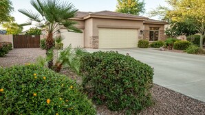A single-story house with a garage, surrounded by a well-maintained garden with various plants and flowers. - Resort Like Home W/Private Heated Swimming Pool / Power Ranch K1 Pickleball (Gilbert)