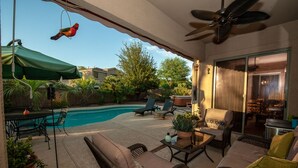 A covered patio with a pool, outdoor furniture, and a bird feeder. - Resort Like Home W/Private Heated Swimming Pool / Power Ranch K1 Pickleball (Gilbert)