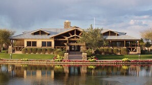 A large, two-story building with a stone facade and a metal roof, surrounded by a well-maintained garden and a reflective water feature in front. - Resort Like Home W/Private Heated Swimming Pool / Power Ranch K1 Pickleball (Gilbert)