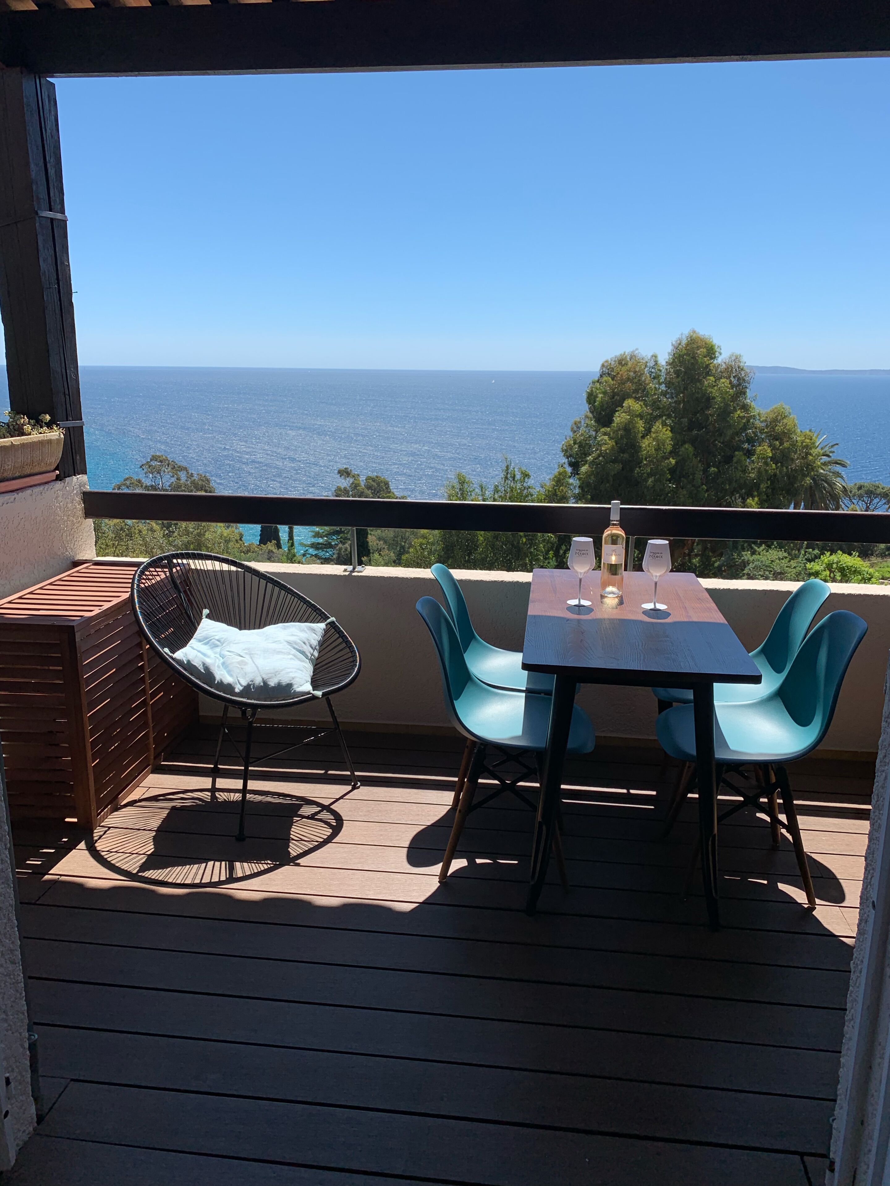 A balcony with a table and chairs, overlooking a scenic view of the sea.