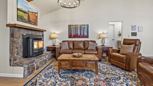 Un salon chaleureux avec une cheminée en pierre, un canapé en cuir marron, un fauteuil inclinable et un tapis à motifs.