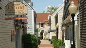 A narrow street lined with buildings, including a hair salon named 'Karma' with a sign advertising hair, facials, and massage services. - Beautifully Renovated Downtown Luxury Condo, a block from the rock!   (Plymouth)