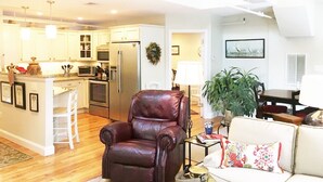 A spacious living area with a leather armchair, a sofa, and a dining table. There is a kitchen with a refrigerator and a dining area with a plant. - Beautifully Renovated Downtown Luxury Condo, a block from the rock!   (Plymouth)