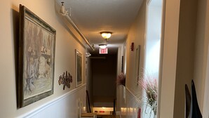 A hallway with a white wainscoting, a wooden bench, a framed painting, and a decorative wall piece. - Beautifully Renovated Downtown Luxury Condo, a block from the rock!   (Plymouth)