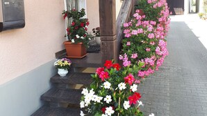 A building with a beige exterior, a wooden staircase, and potted plants with flowers.
