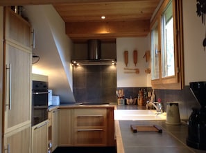 Een moderne keuken met houten kastjes, een rvs afzuigkap en een betegelde achterwand.