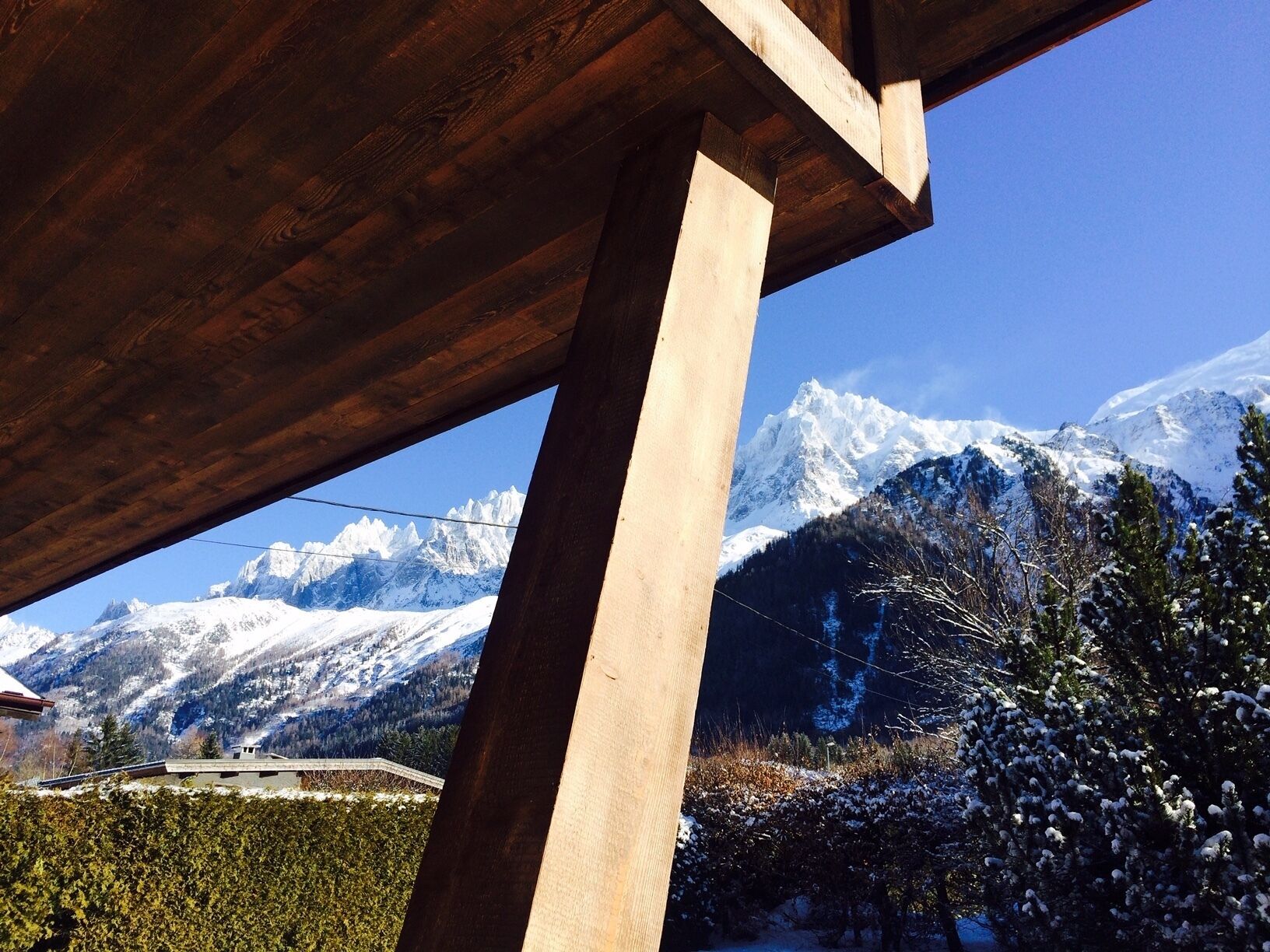 Een houten constructie met uitzicht op besneeuwde bergen en een heldere lucht.