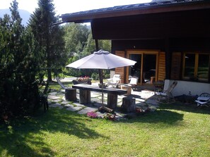Een terras met buitenmeubilair, een tafel en een parasol.