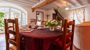 A dining area with a table set for breakfast, wooden chairs, and a vase of flowers.