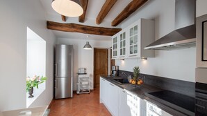 A modern kitchen with white cabinets, a stainless steel refrigerator, and a black countertop.