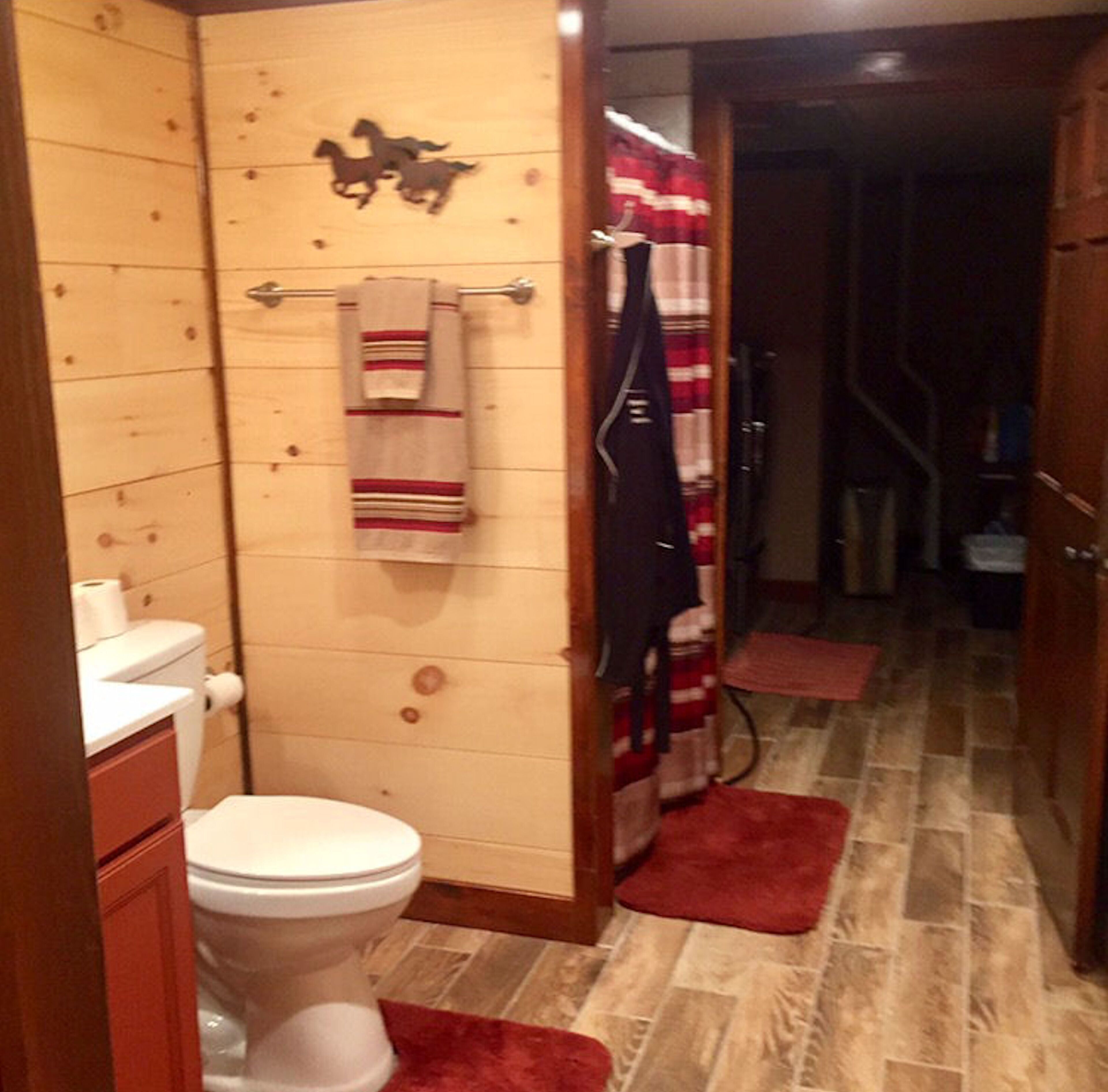 A bathroom with wooden walls, a toilet, a towel rack with a striped towel, and a shower curtain.