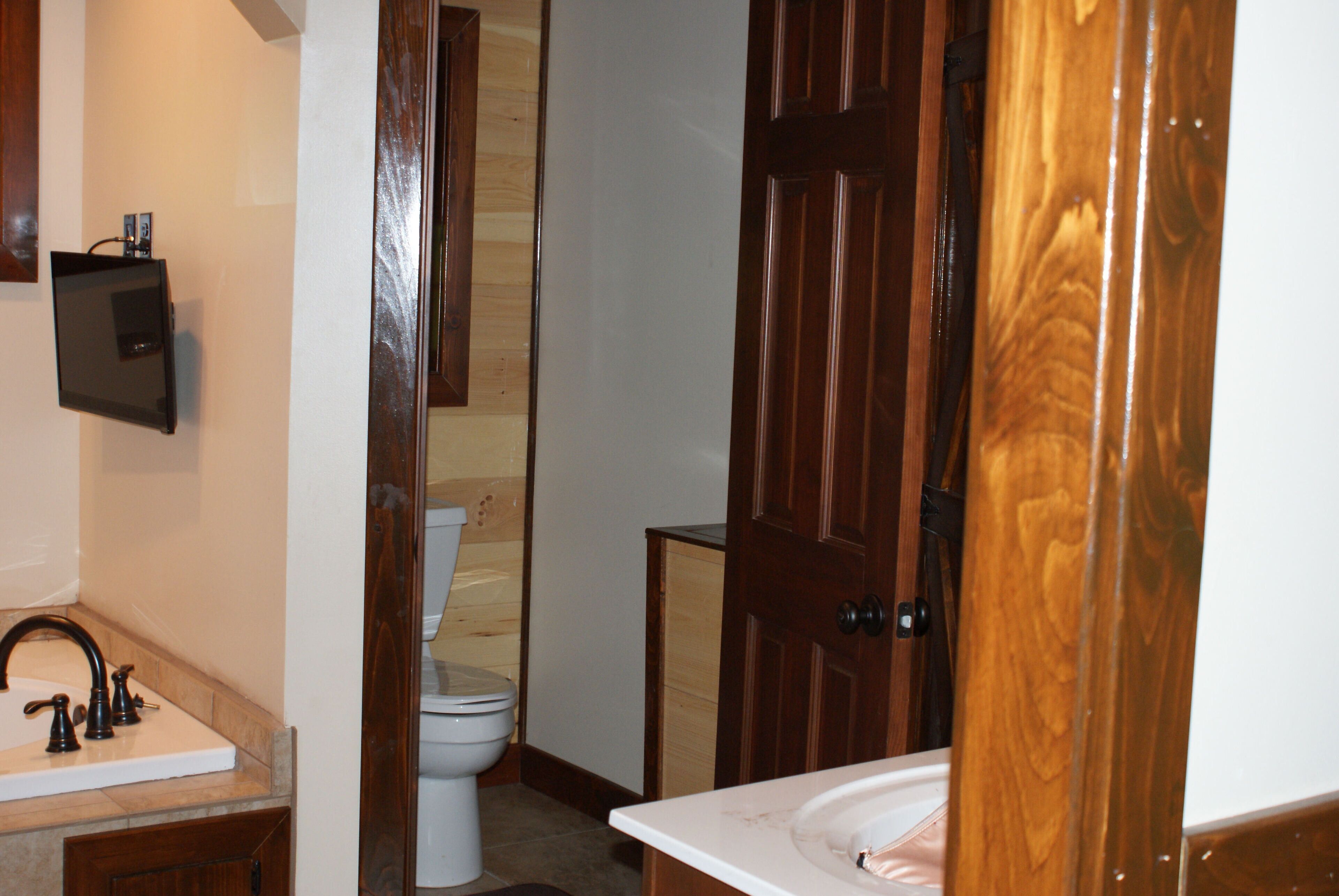 A bathroom with a white sink, a toilet, and wooden doors.