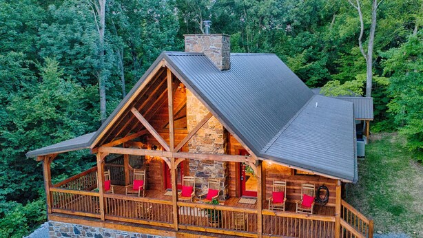 Eine Holzhütte mit steinernen Fundamenten, einer Holzterrasse und mehreren Sitzbereichen mit roten Kissen.