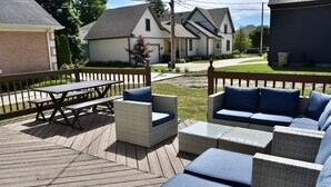 Une terrasse en bois aménagée avec du mobilier d’extérieur, notamment une table et des chaises, ainsi qu’un ensemble de canapés.