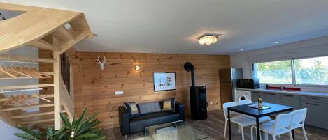 Un interior moderno con una pared de madera, un sofá, una mesa de comedor y una escalera.