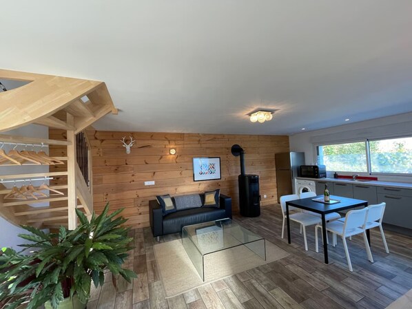A modern interior with a wooden wall, a sofa, a dining table, and a staircase.