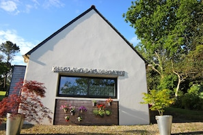 A modern building with a triangular roof, a large window, and a flower display in front.