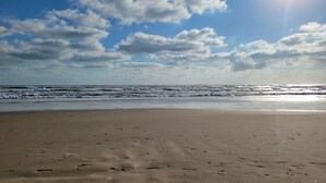 Ein Strand mit Fußabdrücken im Sand und brechenden Wellen.