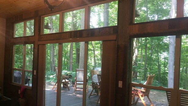 A wooden interior with large windows overlooking a deck area.