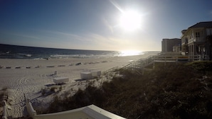 A beach with a clear sky, a sun setting or rising over the ocean, and buildings on the right. - "The Odyssea" - Carillon Beach - Beautiful Home Two Lots From Beach!  (Panama City Beach)