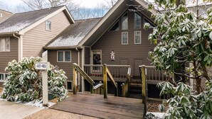 A two-story house with a wooden deck and a mailbox.