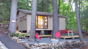 A cabin with a stone foundation, wooden deck, and a fire pit.
