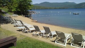 A lakeside view with rows of white lounge chairs and a dock extending into the water.