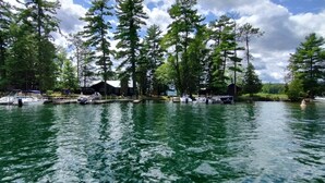 A lake with boats docked, surrounded by tall trees and a small cabin.
