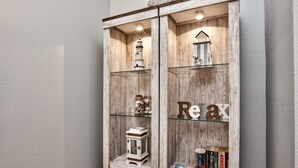 A wooden cabinet with glass shelves containing decorative items like a lighthouse model, a lantern, and books. - Charming, newly reno 1Bdrm condo, minutes from beautiful Clearwater Beach (Clearwater)