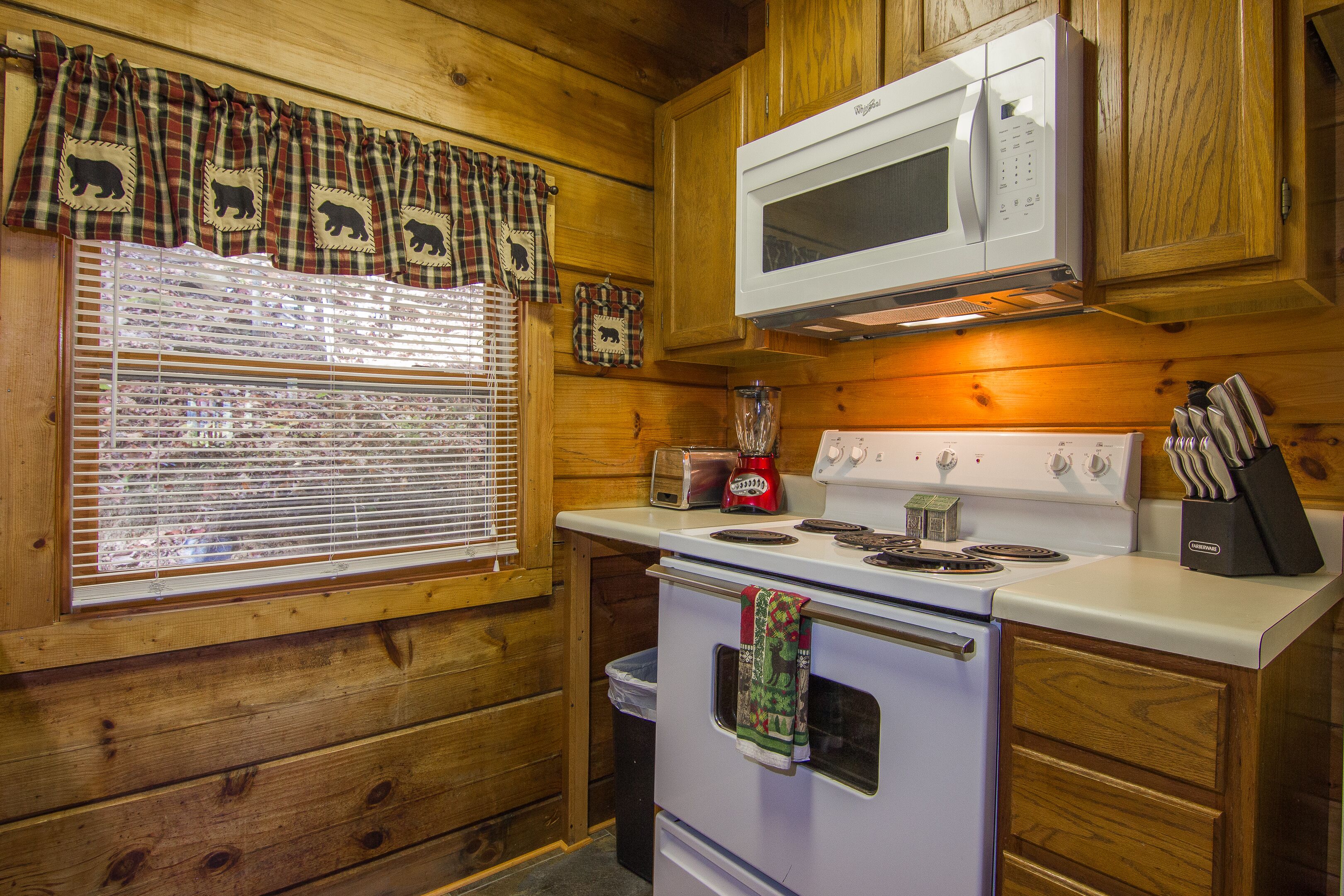 Une cuisine avec des meubles de rangement en bois, un four à micro-ondes, une cuisinière, un grille-pain et un mixeur.