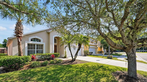A residential house with a well-maintained lawn, a large tree, and a garage. - 4BR Disney Oasis: Private Screened Pool + FREE Pool Heat! (20 Min to Parks) (Kissimmee)