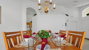 A dining room with a wooden table set for four, a chandelier, and a potted plant on the table. - 4BR Disney Oasis: Private Screened Pool + FREE Pool Heat! (20 Min to Parks) (Kissimmee)