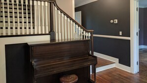 A grand piano in a spacious room with a dark wall and a wooden staircase. - Stonehouse w/ Hot Tub, Walk to GAP Trail & Town (Confluence)