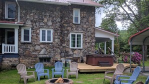 A stone house with a deck, outdoor seating, and a fire pit. - Stonehouse w/ Hot Tub, Walk to GAP Trail & Town (Confluence)