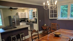 A modern kitchen with white cabinets, a wooden dining table, and a chandelier. - Stonehouse w/ Hot Tub, Walk to GAP Trail & Town (Confluence)