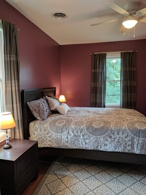 A bedroom with a bed, two bedside lamps, a ceiling fan, and a window with curtains. - Stonehouse w/ Hot Tub, Walk to GAP Trail & Town (Confluence)