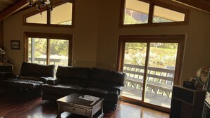Un salon spacieux avec un canapé en cuir, une table basse et une grande fenêtre donnant sur une terrasse.