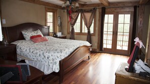 Une chambre à coucher avec un lit en bois, un ventilateur de plafond et un bureau avec un ordinateur.