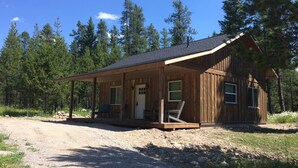 Une cabane en bois avec une véranda, une porte et des fenêtres.
