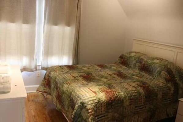 A bedroom with a bed, a nightstand, and a window with curtains. - 3 Bedroom, 2 Bath, Hike to Downtown, Porch, FREE Wi-Fi, Wash/Dryer, and Parking (Athens)